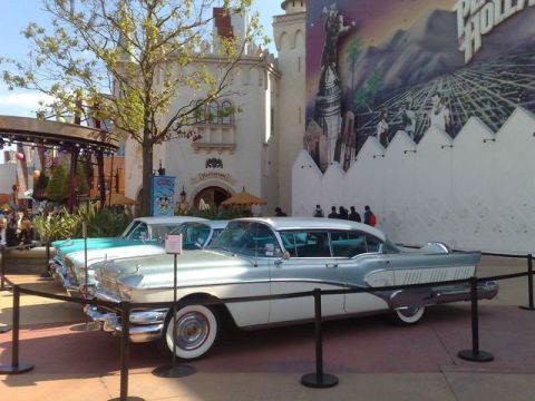 1991 Ford LTD Crown Victoria - Two vintage sedans, likely from the late 1950s, are parked in front of a themed building with a mural.