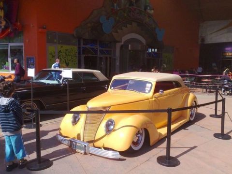 1991 Ford LTD Crown Victoria - Two classic cars are displayed outside a building with Disney branding.