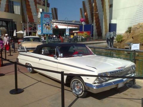 1991 Ford LTD Crown Victoria - A white convertible with a black top and red interior is parked on display, with another vintage car behind it.