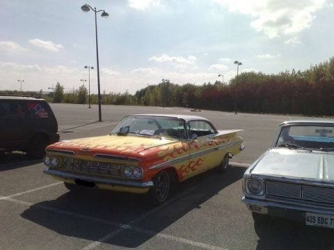 1991 Ford LTD Crown Victoria - A classic 1959 Chevrolet Impala with flame decals is parked next to another vehicle.
