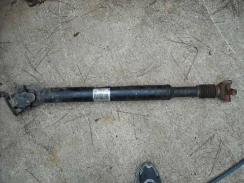 1979 Ford F-150 - A driveshaft is shown lying on a concrete surface with pine needles scattered around.