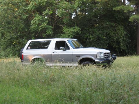 1994 Ford Bronco - This 1994 Ford Bronco is parked in a grassy area with trees in the background.
