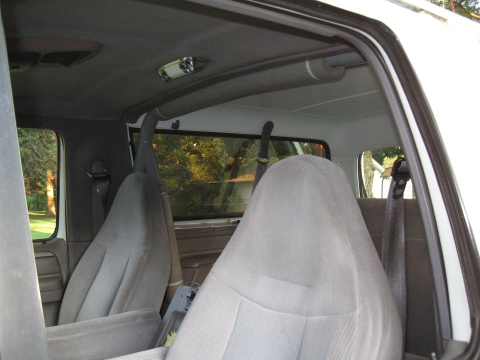 Interior shot of a white SUV, showing front seats and roll bar