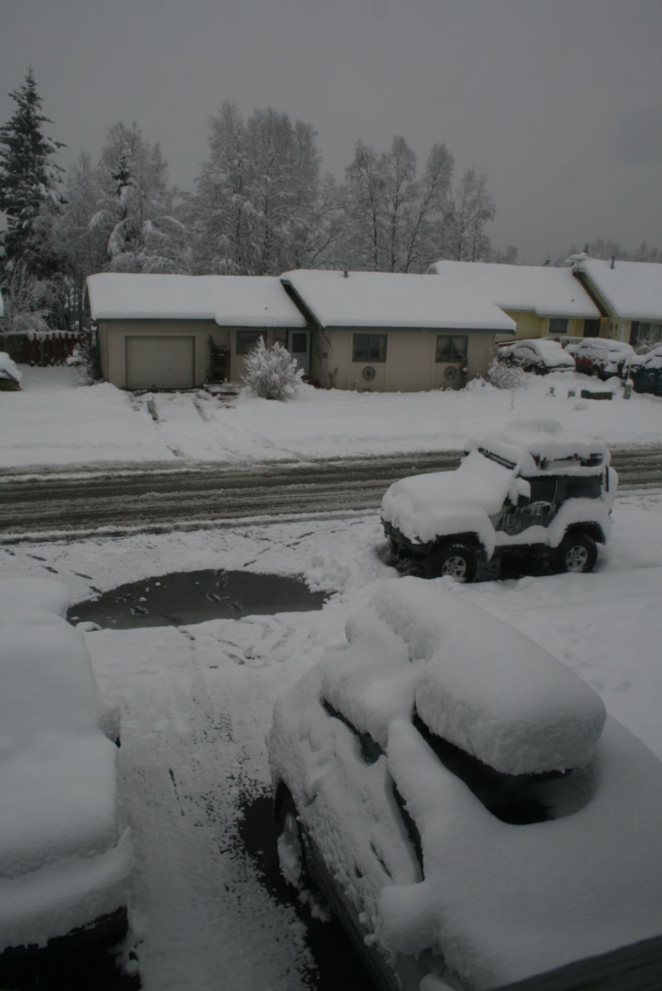 2003 Jeep TJ covered in snow, parked next to other snow-covered vehicles