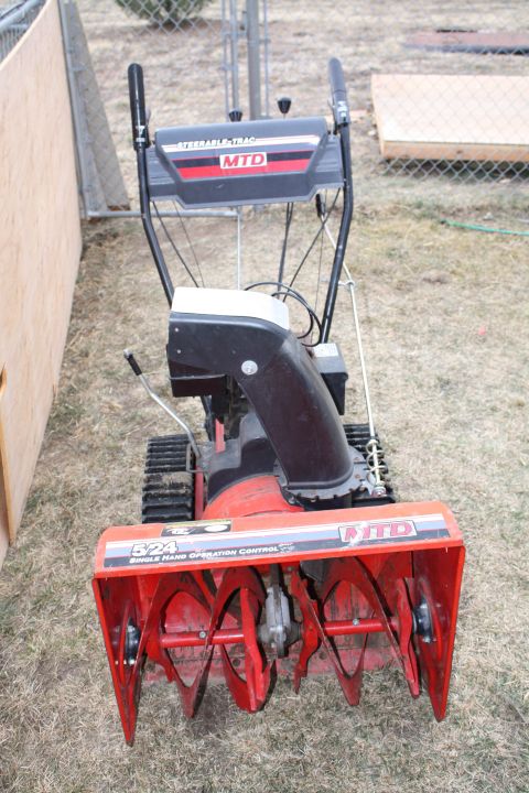 2003 Jeep TJ - This MTD snow blower features a red auger and a black housing, with tracks for mobility.