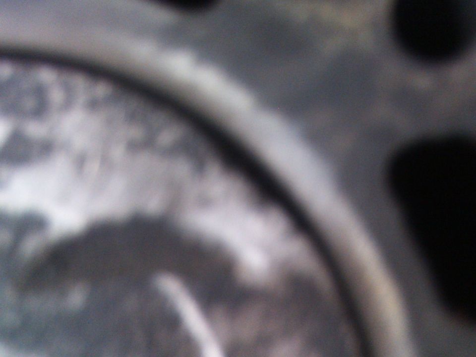 Close-up of a metal engine component with some texture and a dark circular area
