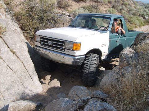 1989 Ford Bronco - Ford Bronco is shown off-roading through a rocky landscape.