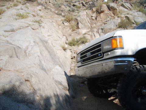 1989 Ford Bronco - A white Ford truck maneuvers through a narrow, rocky path.