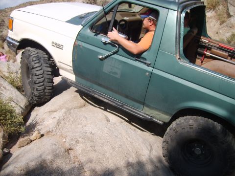 1989 Ford Bronco - This two-tone Ford F-250 is navigating a rocky trail with its driver behind the wheel.