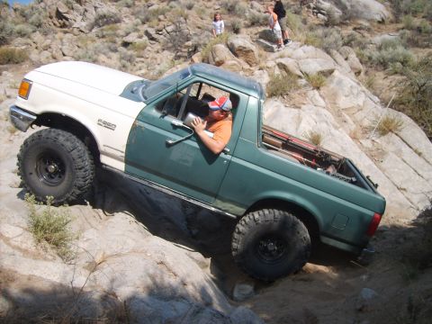 1989 Ford Bronco - This modified Ford Bronco is tackling a challenging off-road course with steep inclines and large rocks.