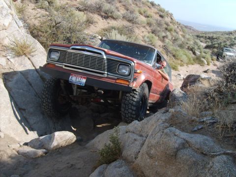 1989 Ford Bronco - Jeep Cherokee Chief tackling difficult off-road terrain on a sunny day.