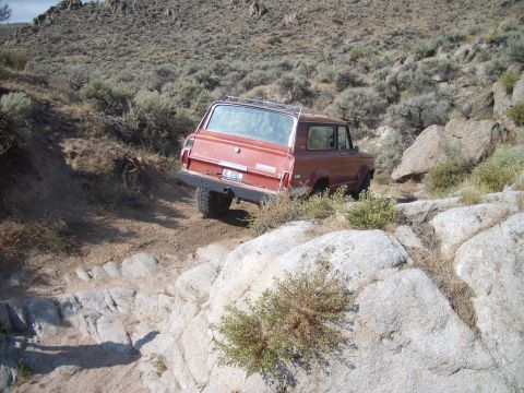 1989 Ford Bronco - A vintage red SUV tackles a challenging rocky terrain on an off-road adventure.