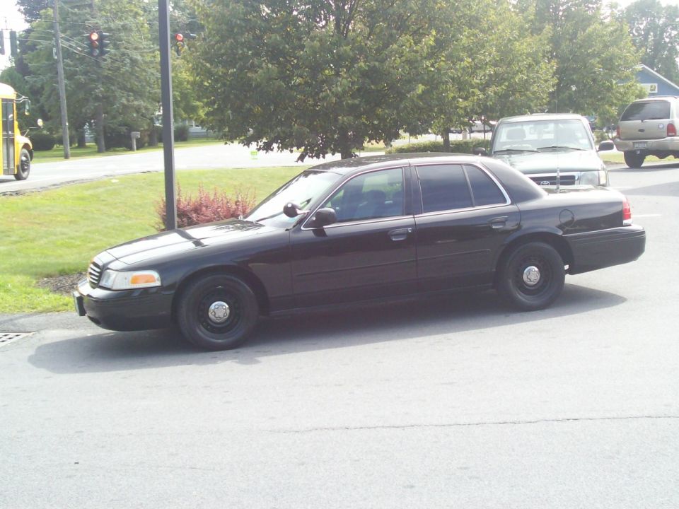 Black Ford Crown Victoria sedan parked at an intersection