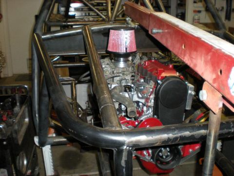 Suzuki Samurai - The engine bay of a custom-built off-road vehicle, a red engine and exposed roll cage.