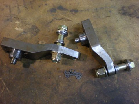 Suzuki Samurai - Two metal steering knuckle parts are laid out on a workbench with a small Suzuki Samurai cutout.