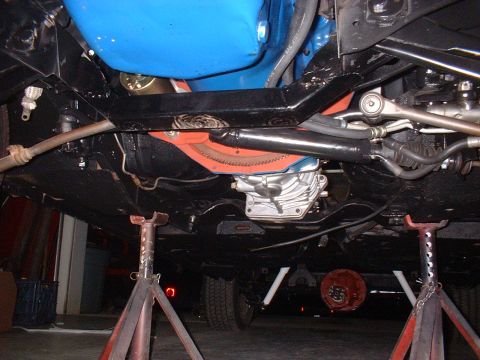 1970 Ford Torino - A vehicle's undercarriage is viewed from below, supported by red jack stands.