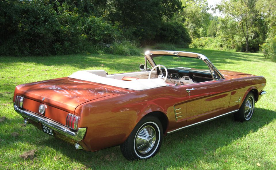 Copper 1966 Ford Mustang convertible, top down, rear three-quarter view on grass