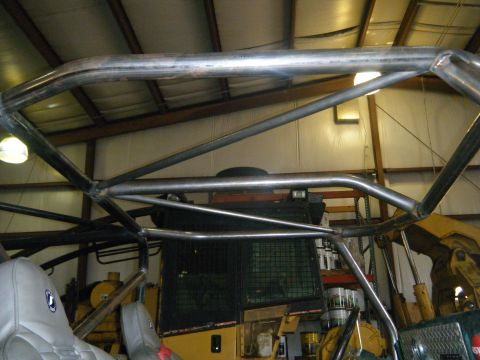 1978 Ford Bronco - A custom roll cage is installed inside a vehicle, with heavy equipment visible in the background.
