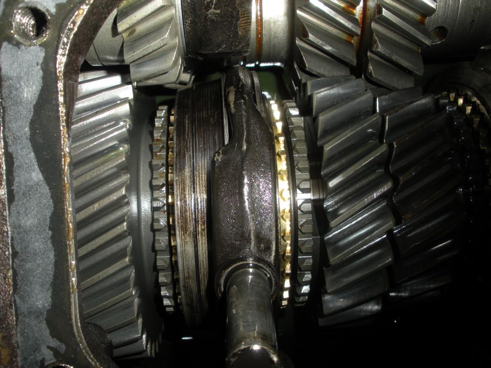 Disassembled manual transmission internals with helical gears and brass synchro rings