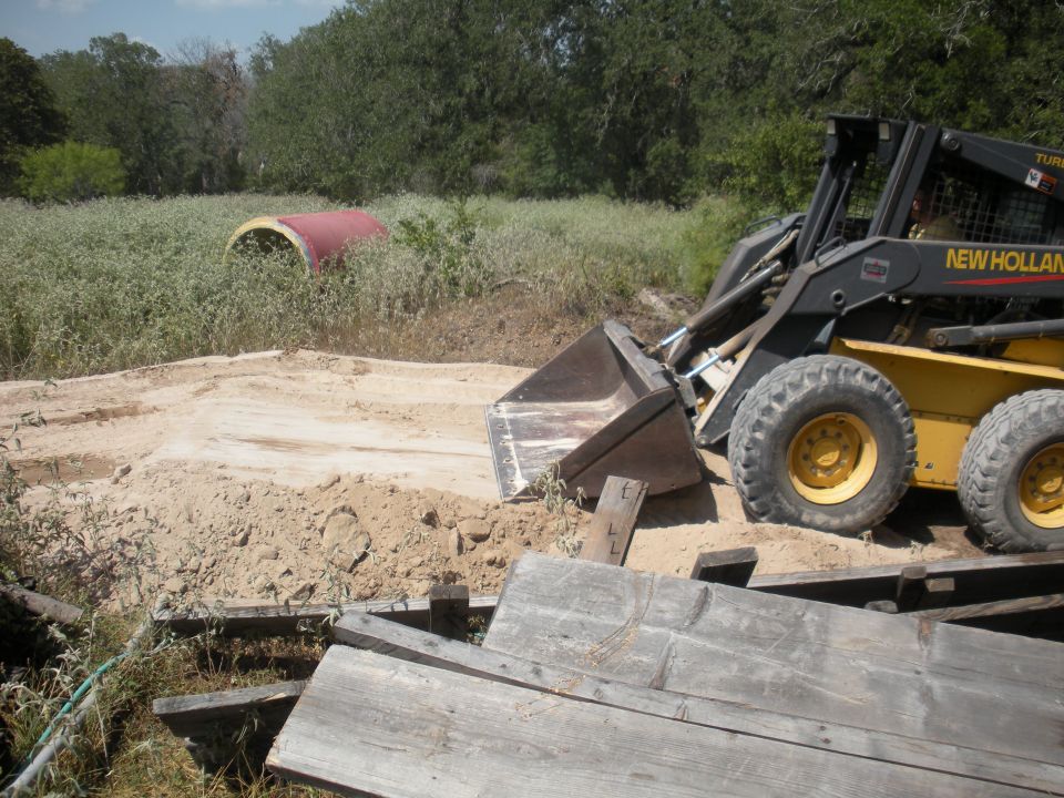 Yellow New Holland skid steer loader with bucket, side view