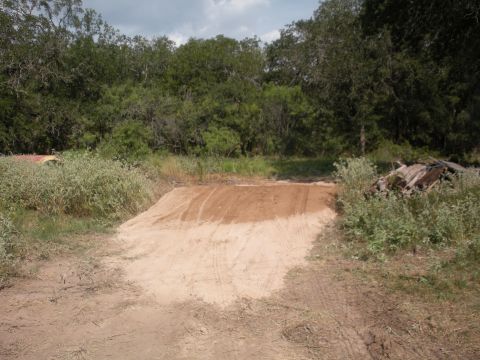 1996 Ford Bronco - A dirt ramp is set up in a natural outdoor setting with trees and vegetation.