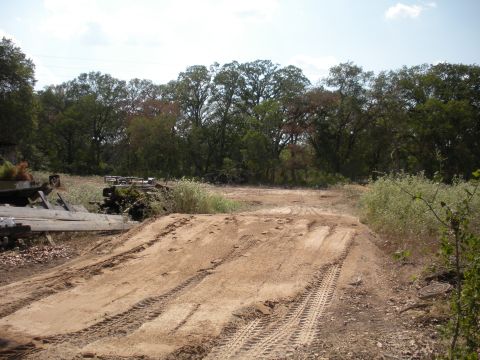 1996 Ford Bronco - A dirt track with tire marks leads through a wooded area with some debris visible.