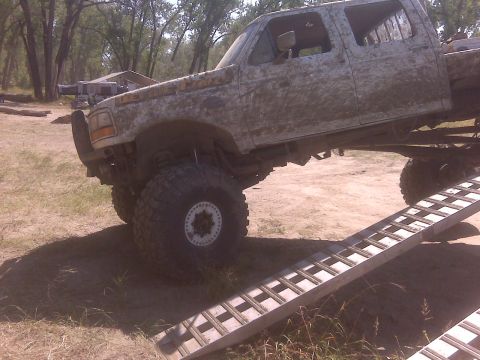 1992 Ford F-350 - This heavily modified pickup truck is covered in mud and positioned on a metal ramp.