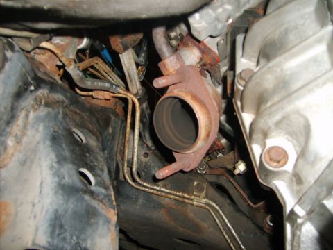1993 Ford Crown Victoria - Underside view of rusted exhaust pipe and engine components with visible hoses.
