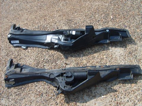 1993 Ford Crown Victoria - Two black automotive plastic parts with metal components are shown against a gravel background.