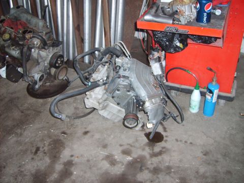 1993 Ford Crown Victoria - Two V8 engines are disassembled and sit on a dirty garage floor next to a red tool cart.