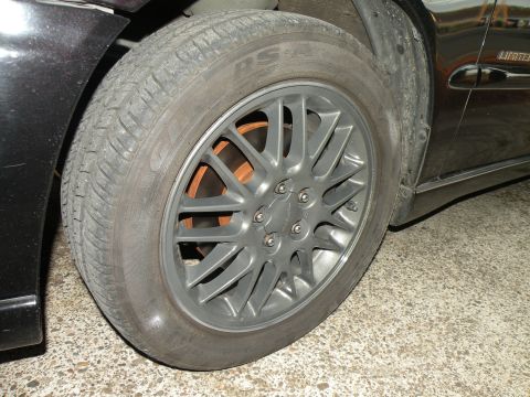 1998 Subaru Legacy - The photo shows a close-up of a car's wheel and tire, focusing on the rim and brake rotor.