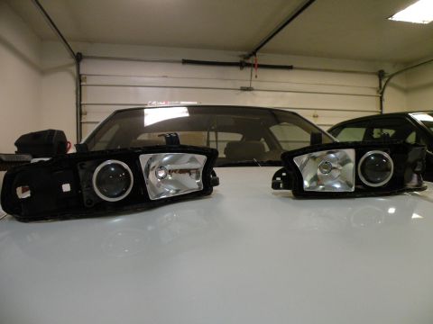 1998 Subaru Legacy - A pair of custom headlights with projector lenses are displayed in a garage setting.