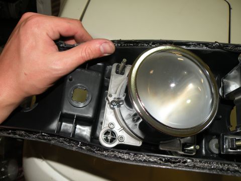 1998 Subaru Legacy - Close-up of a car headlight assembly being held by a hand.