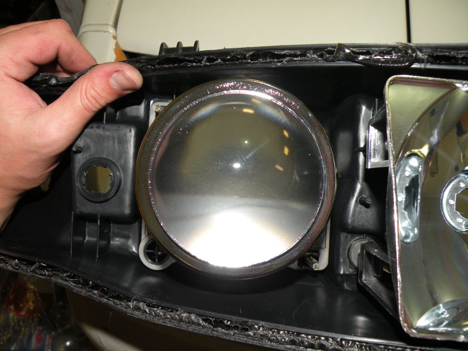 Headlight assembly with chrome bezel and clear lens, held by a hand