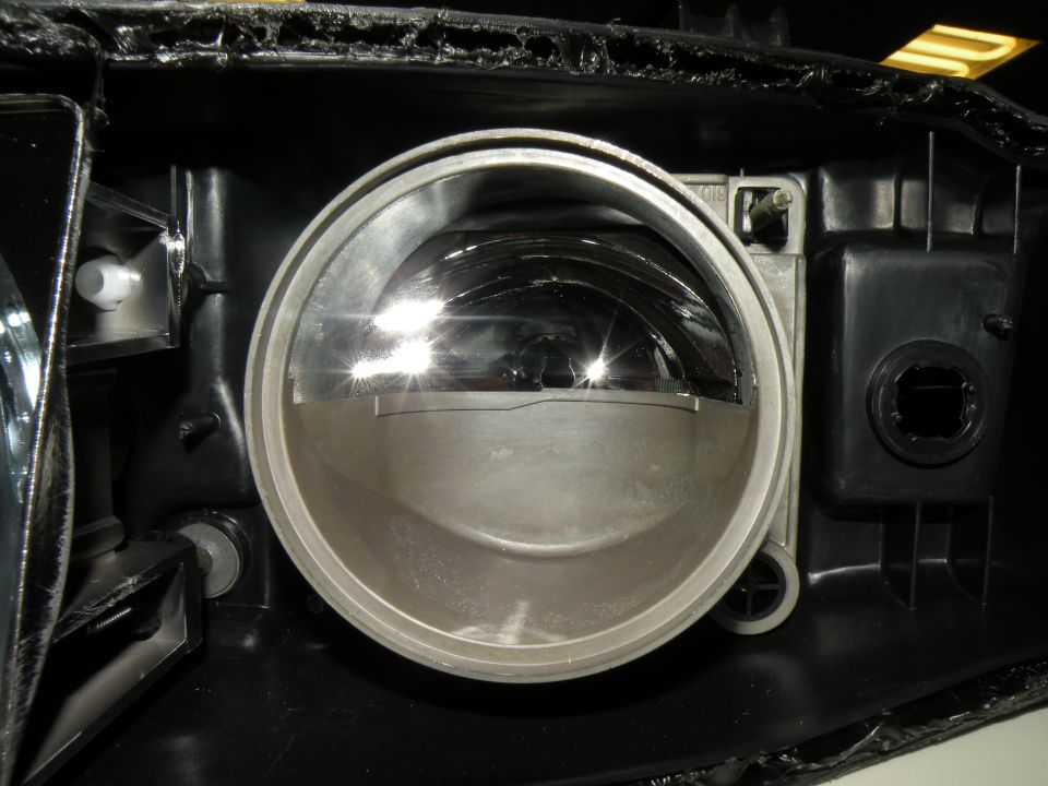 Close-up of a car's headlight housing, showing the reflector and mounting points