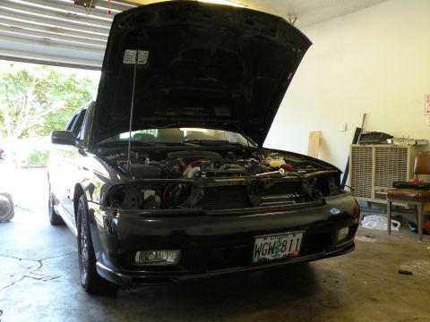 1998 Subaru Legacy - A black 1998 Subaru Legacy sedan is parked in a garage with its hood open, revealing the engine compartment.