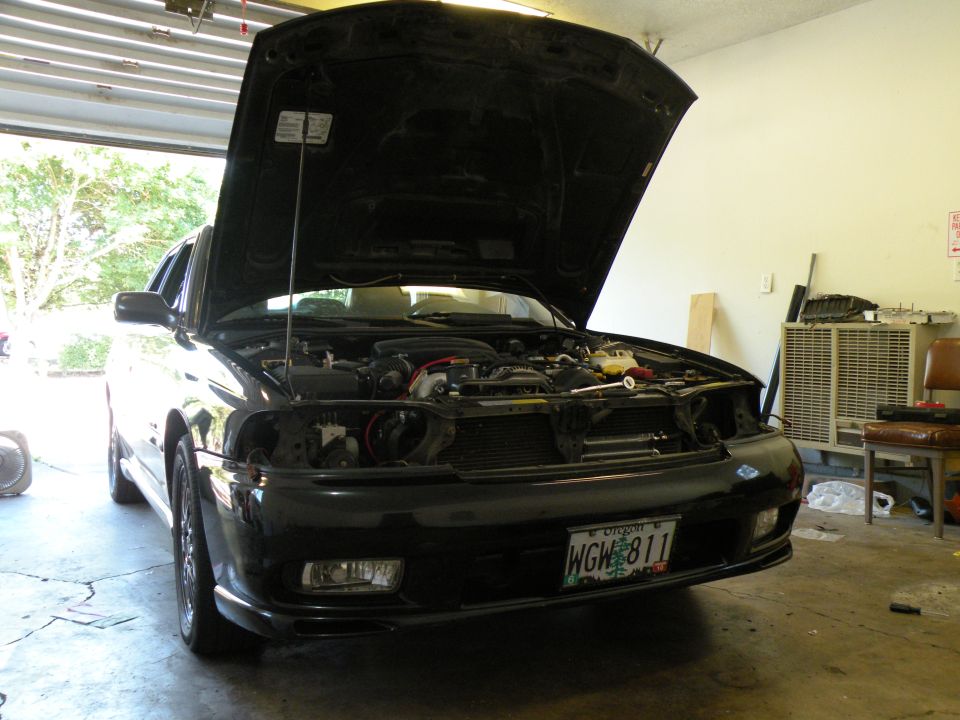 Black 1998 Subaru Legacy sedan with hood open, front view, showing engine and front bumper with license plate WGW 811