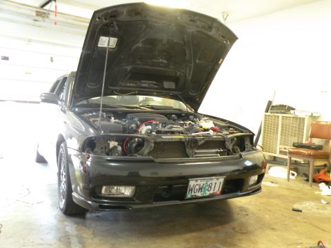 1998 Subaru Legacy - Front view of a 1998 Subaru Legacy in a garage, hood open, revealing the engine.