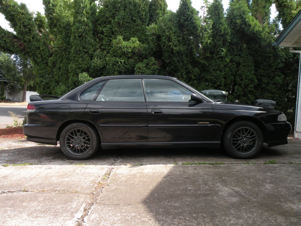 Black 1998 Subaru Legacy sedan, side view. Limited trim badge visible