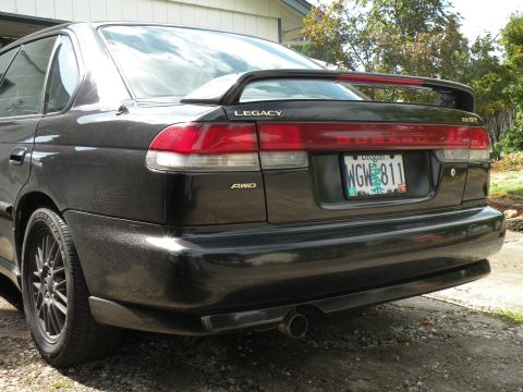 1998 Subaru Legacy - Rear view of a black 1998 Subaru Legacy sedan with a spoiler and AWD badge.