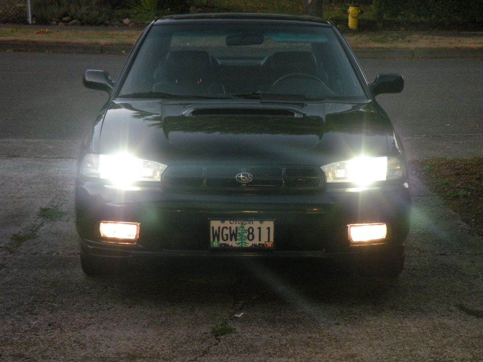 Dark green 1998 Subaru Legacy with headlights and fog lights on, front view