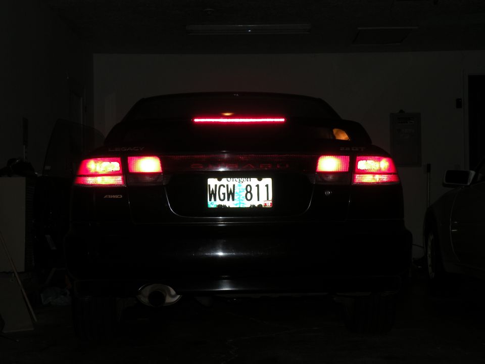 Rear of a black Subaru Legacy with brake lights on. License plate reads WGW 811
