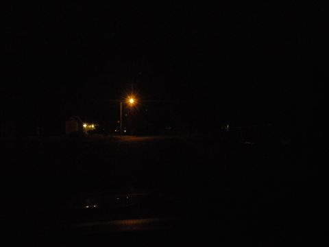 1998 Subaru Legacy - A street lamp casts an orange glow on a dark road at night, with a building visible in the background.