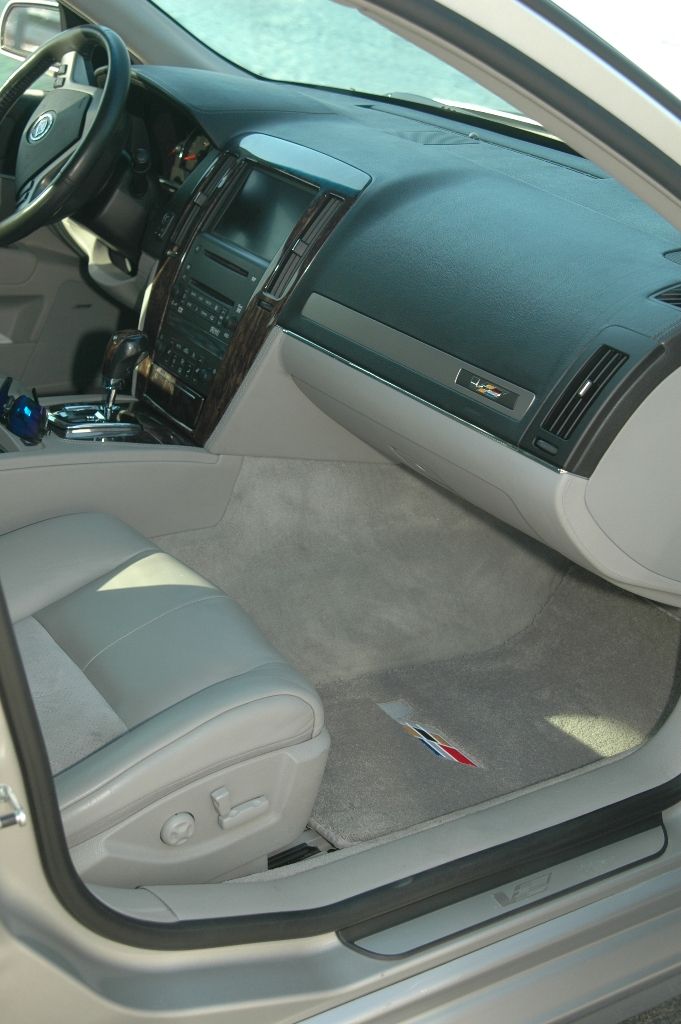 Cadillac interior with wood trim dash, gray leather seats and crest floor mat