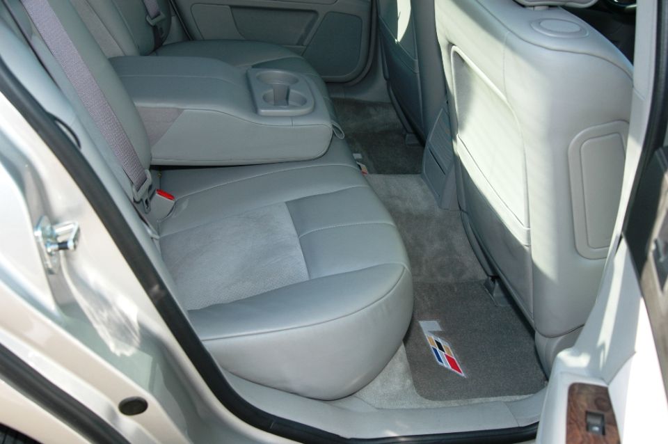 Gray leather rear seats of a Cadillac sedan with crest floor mat