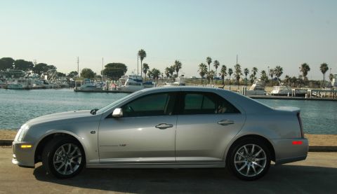 2006 Cadillac STS - A silver 2006 Cadillac STS sedan is parked near a harbor with boats and palm trees in the background.