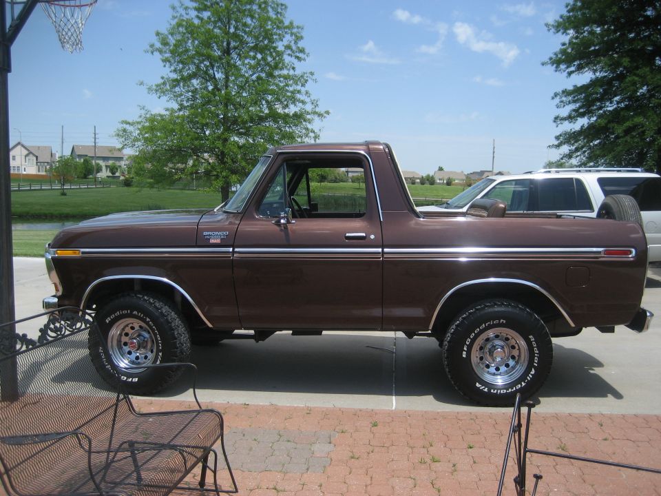 Brown Ford Bronco in side profile on driveway with chrome wheels and all-terrain tires