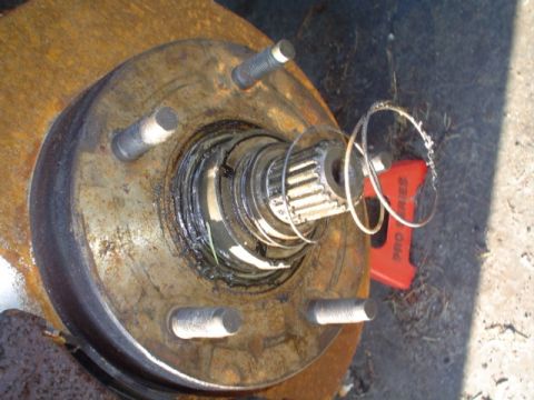 1988 Ford Bronco - Rusty wheel hub assembly and brake rotor, with a tool in the background.