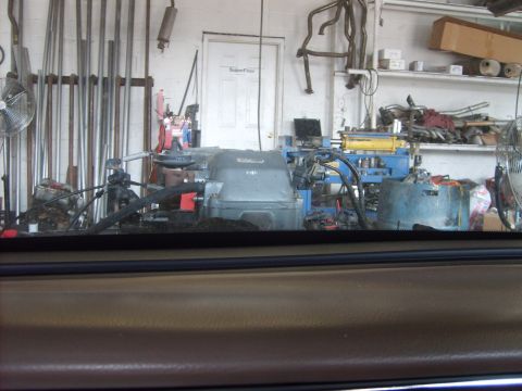 1993 Ford Crown Victoria - View from inside a car shows a workshop with an engine and various tools and equipment.