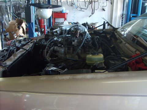 1993 Ford Crown Victoria - The engine compartment of a car is shown in a repair shop, with various mechanical parts exposed.